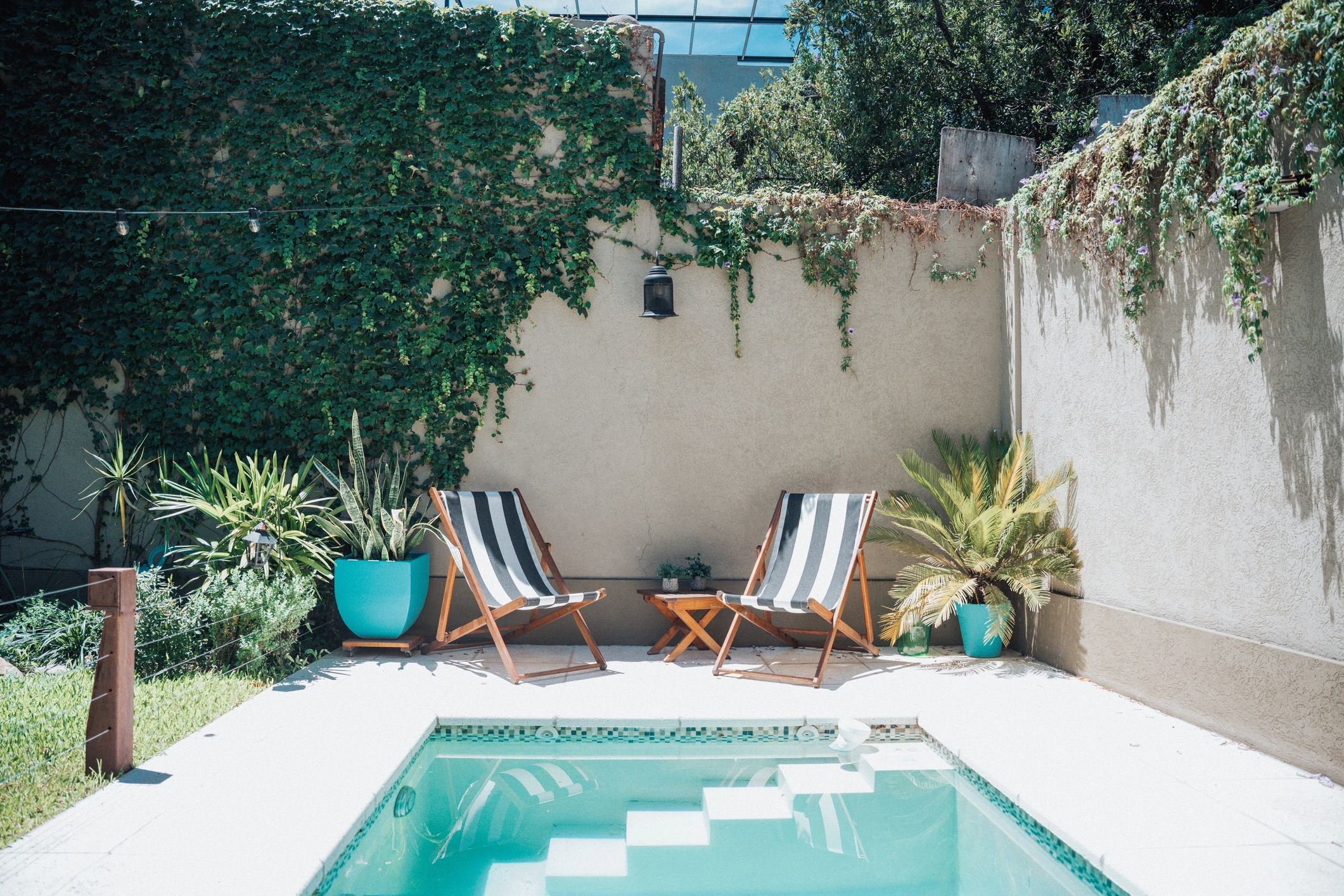 Outdoor poolside patio with sun loungers in a landscaped backyard